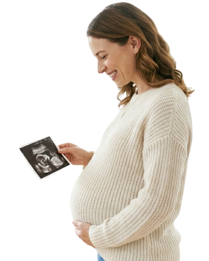 Pregnant woman smiling looking down at her baby scan photo