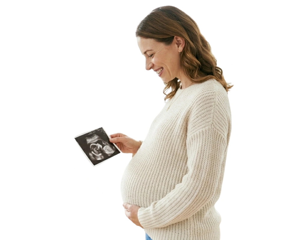 Pregnant woman smiling looking down at her baby scan photo